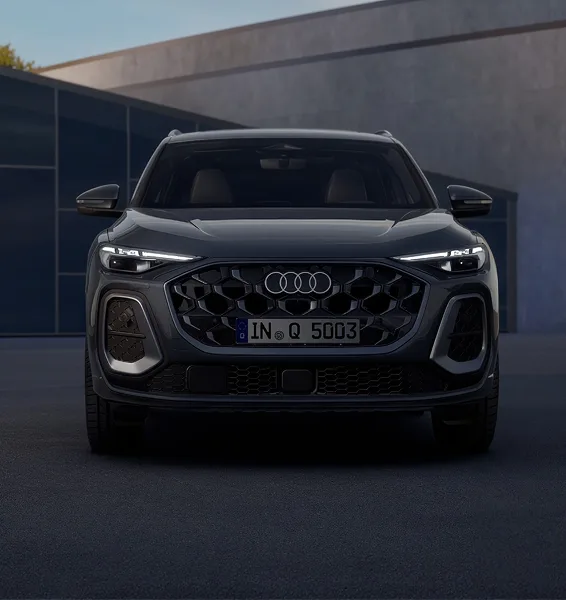 Dark grey Audi Q5 photographed head-on at dusk with its LED headlights lit
