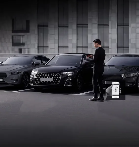 Driver standing beside a parking space using a phone to park the Audi Q8 remotely