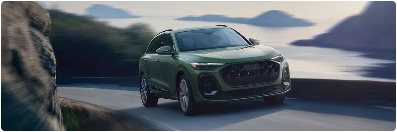 Dark green Audi Q5 driving a coastal mountain road toward the camera