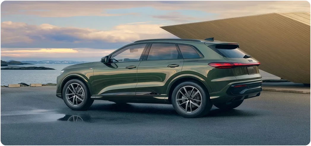 Green Audi Q5 parked beside the water at dusk, seen in profile