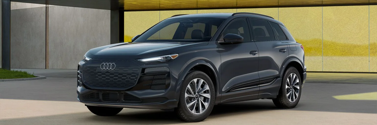Grey Audi Q6 e-tron front three-quarter view in front of a yellow wall