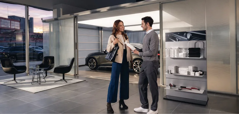 Audi service advisor talking with a customer beside a vehicle in the service drive