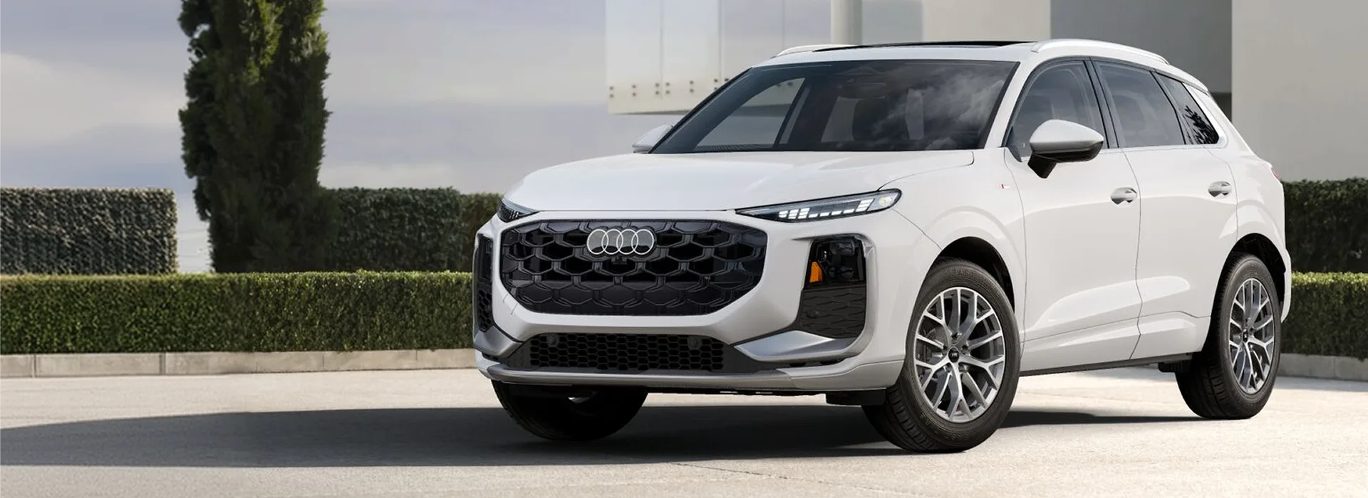 White 2027 Audi Q3 parked on a driveway outside a modern house, seen from the front three-quarter angle