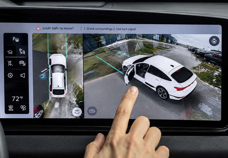 Finger tapping the MMI touch display showing surround view camera images of a white Audi A6
