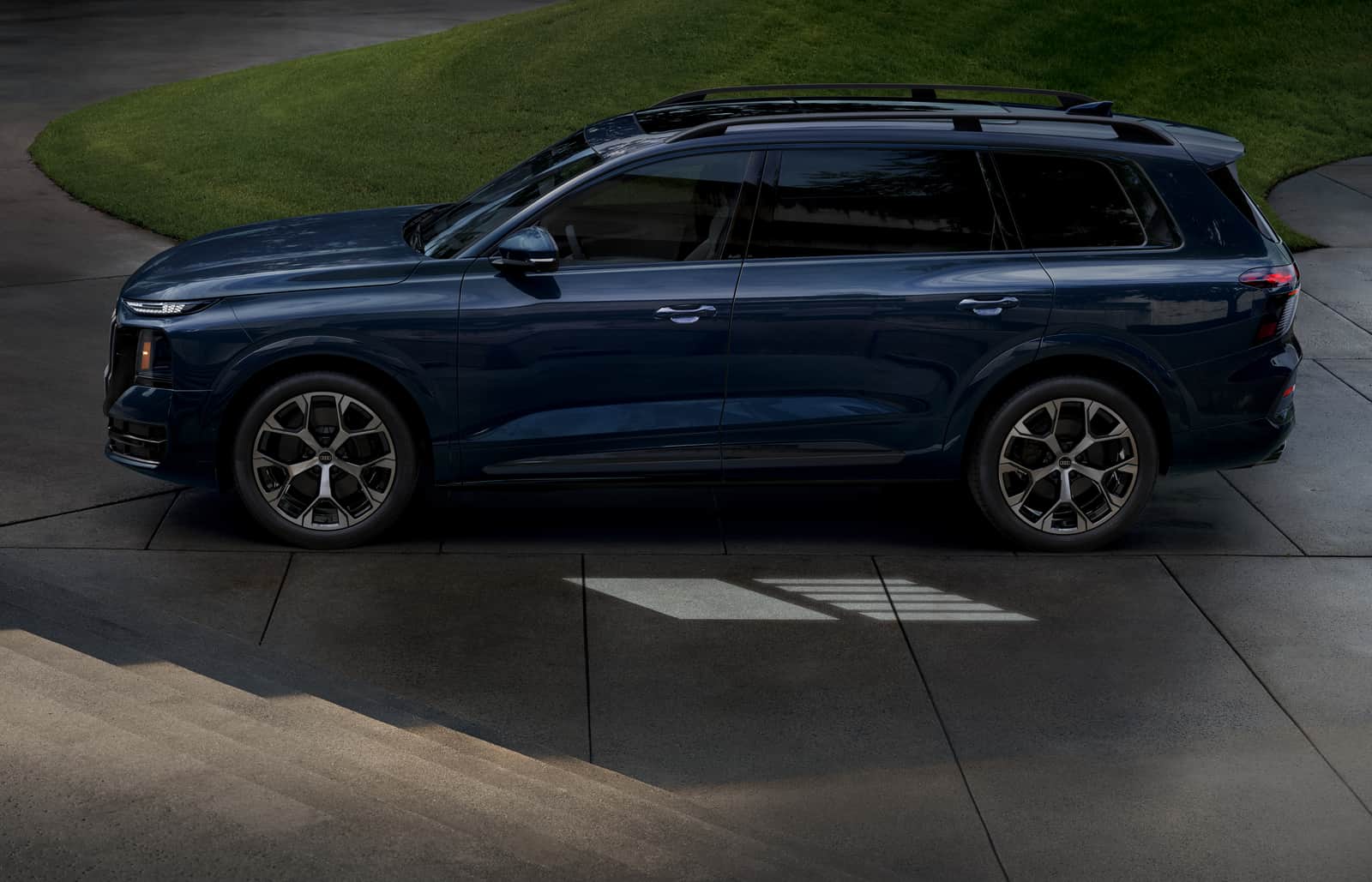2027 Audi Q9 side profile on a stone driveway showing the full body line and wheel design
