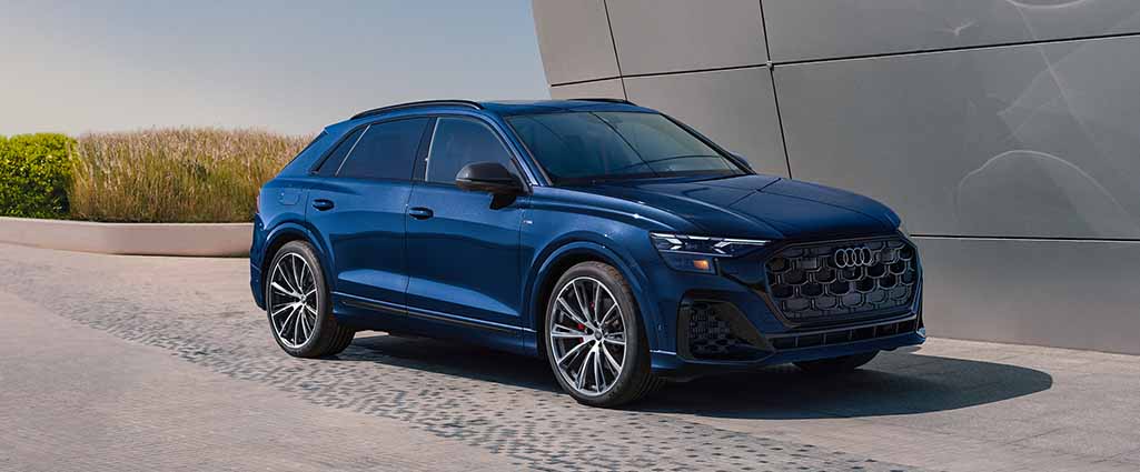 Blue Audi Q8 parked beside a curved metal building