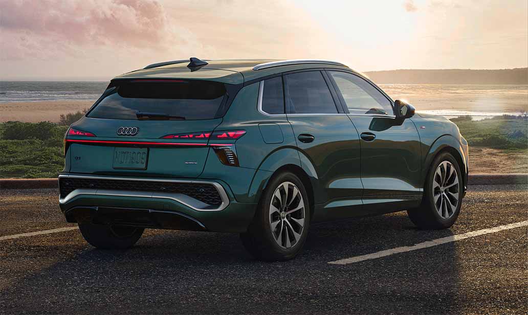 Rear angle of the 2026 Audi Q3 parked near a beach at sunset, highlighting sculpted tailgate, full-width LED taillights, and sporty rear diffuser.
