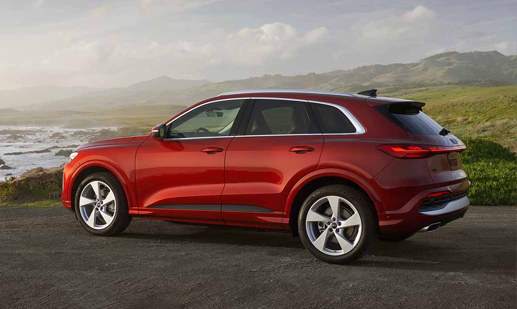 Audi Q5 parked overlooking the ocean with the sun setting in the background.