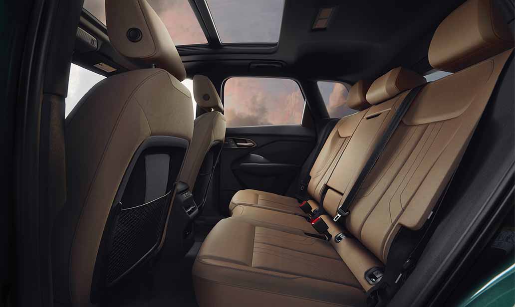 Interior view of the 2026 Audi Q3's rear seats, featuring premium tan leather upholstery, a panoramic sunroof, and spacious legroom with modern rear climate vents.