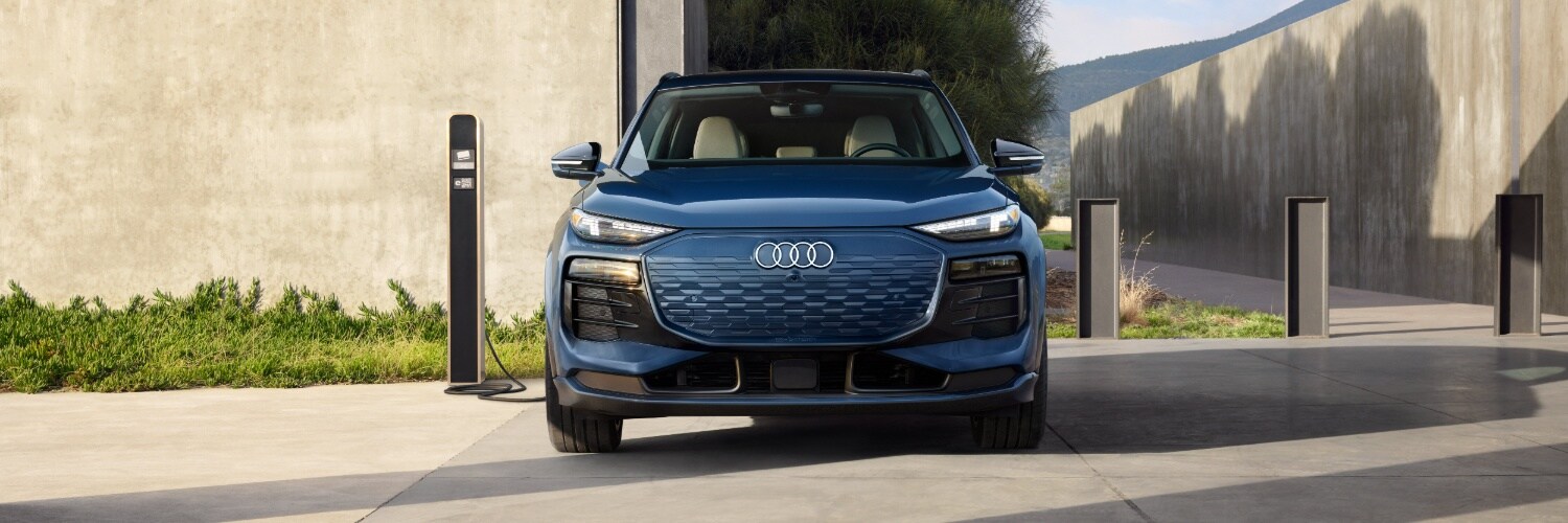Q6 e-tron Blue Q6 e-tron head on view at a charging station
