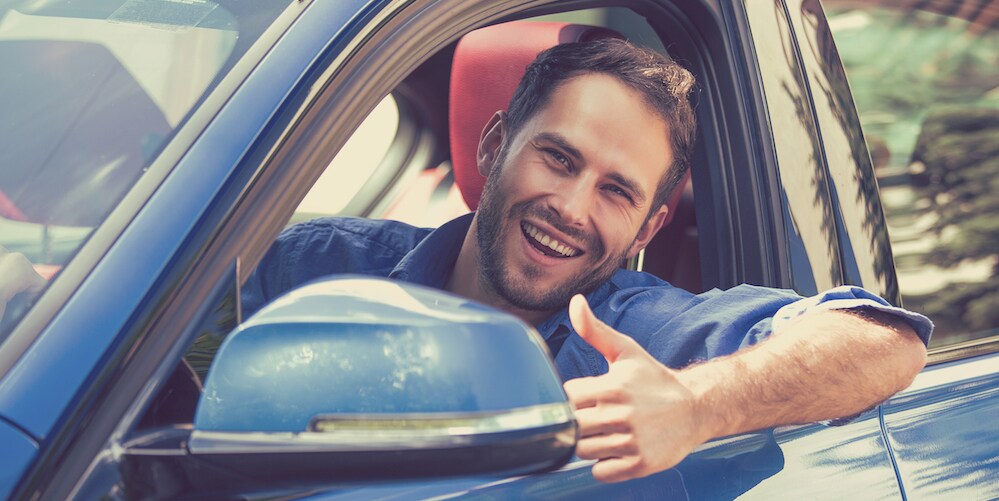 Man Giving Thumbs Up After Buying a Used Car