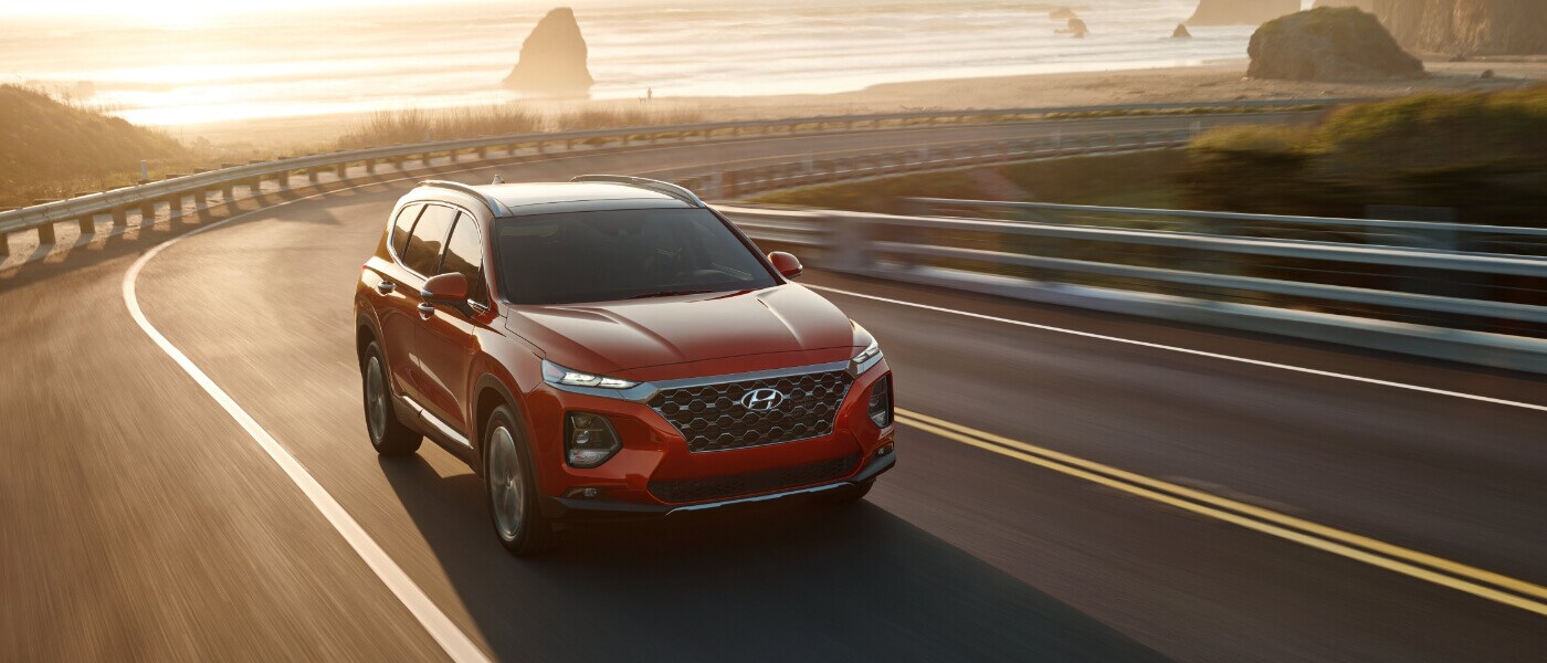 2020 Hyundai Santa Fe in red driving on a highway in the mountians