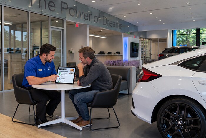 A customer reviewing a Carfax Vehicle History Report with a salesperson at AutoFair Honda