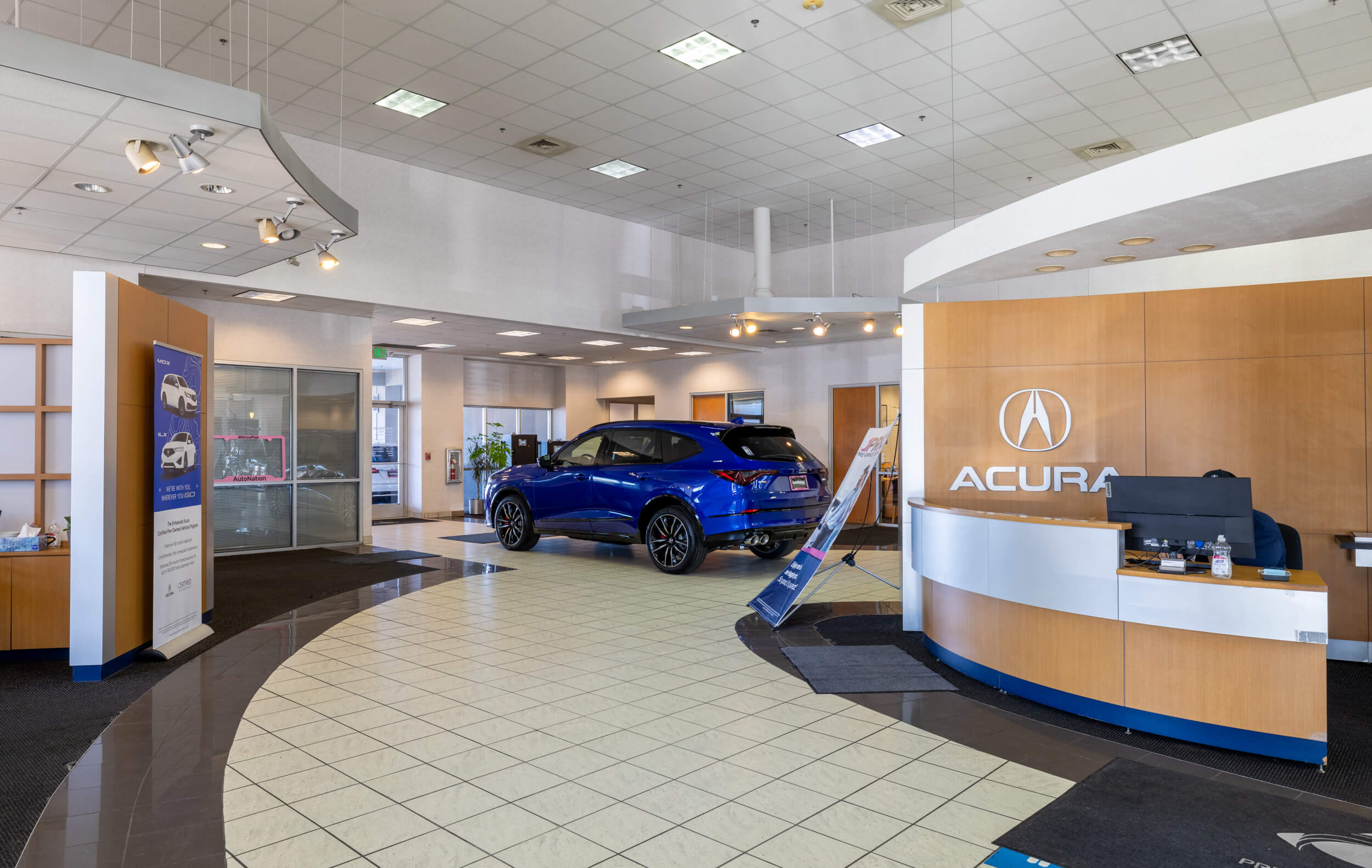 Find out about buying, servicing, and financing Acura vehicles at AutoNation Acura Colorado Springs Interior of AutoNation Acura Colorado Springs with a frame displaying the welcome desk, some offices, and a blue Acura SUV on the showroom floor