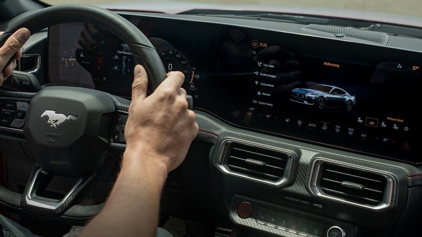 Interior shot of a Ford Mustang showing the steering wheel and command console, with touchscreen.