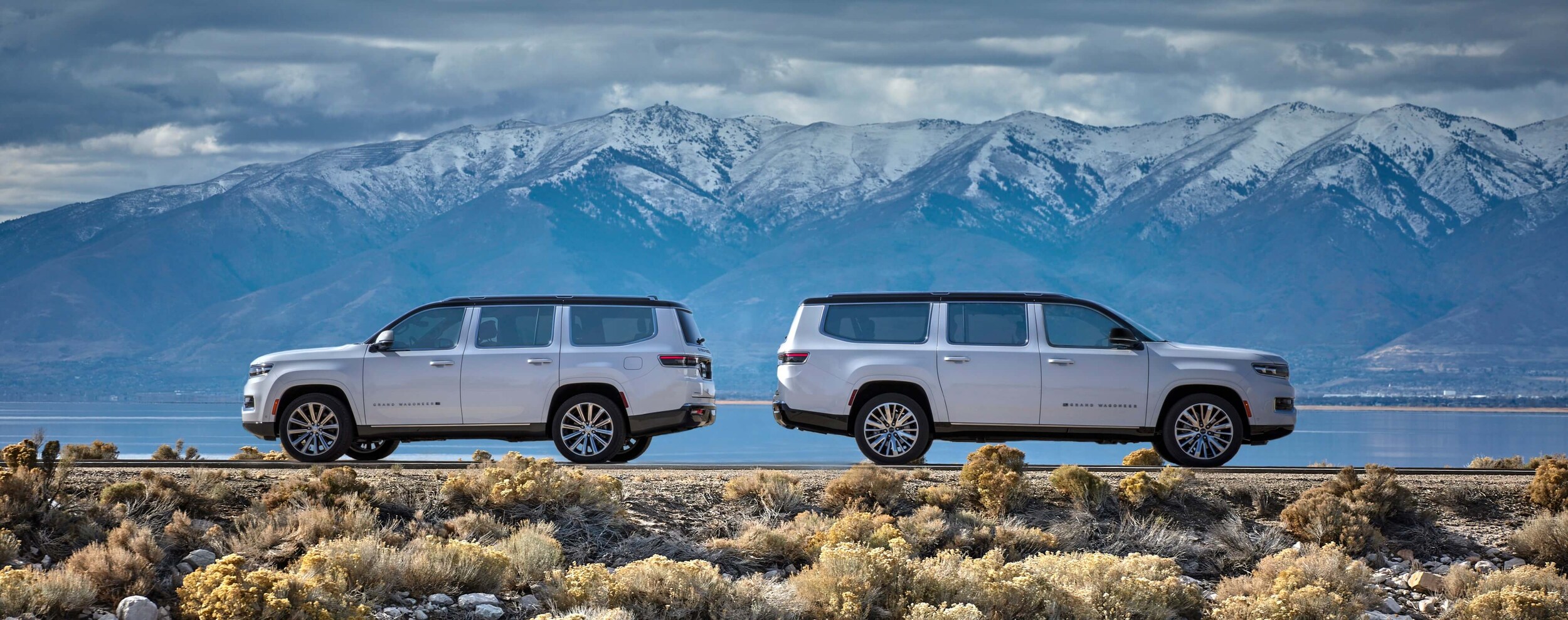 Build and price your Chrysler, Dodge, Jeep, or Ram today at AutoNation Chrysler Dodge Jeep Ram Spring! Two Grand Wagoneer vehicles sitting in front of a snowy mountain range