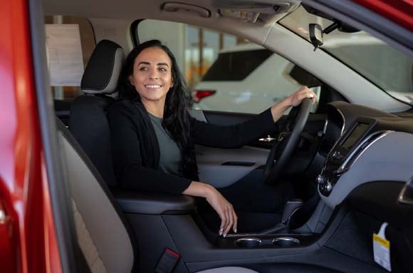 Decode the automotive industry with our glossary of terms Image of a woman smiling in the driver's seat of a red car