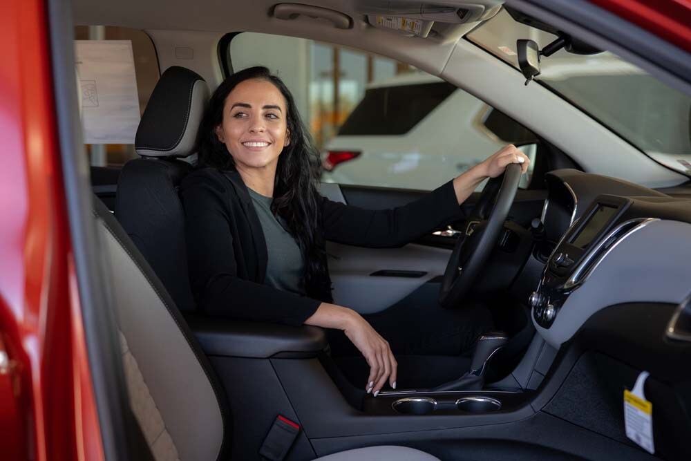 Get automotive glossary terms defined Image of a woman smiling in the driver's seat of a red car