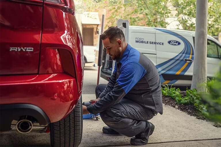 Ford Technician servicing a Ford vehicle in a driveway