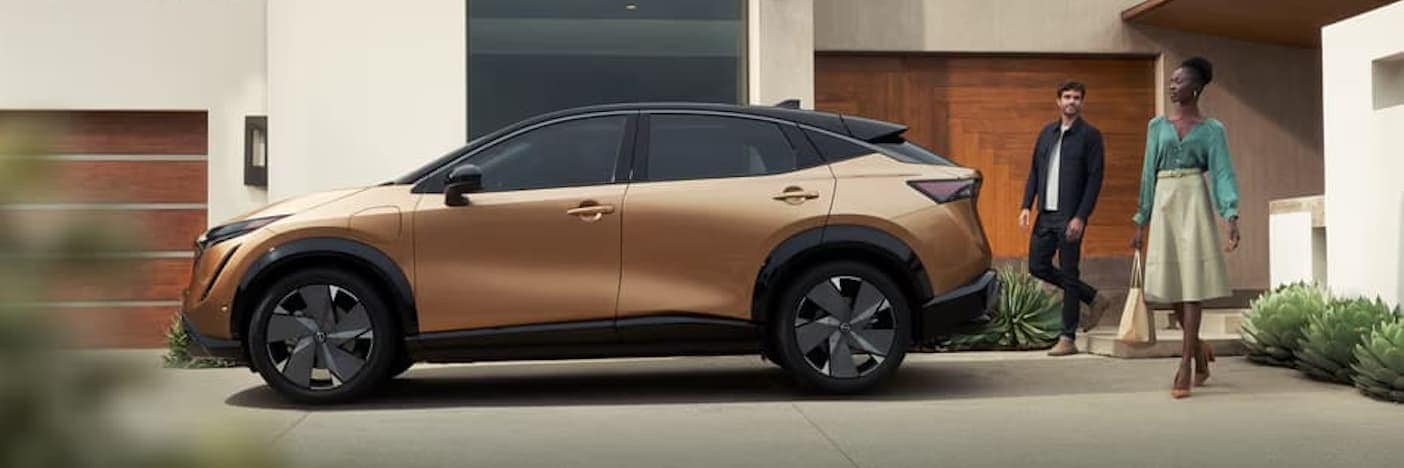 Side view of a Nissan ARIYA EV outside a modern home