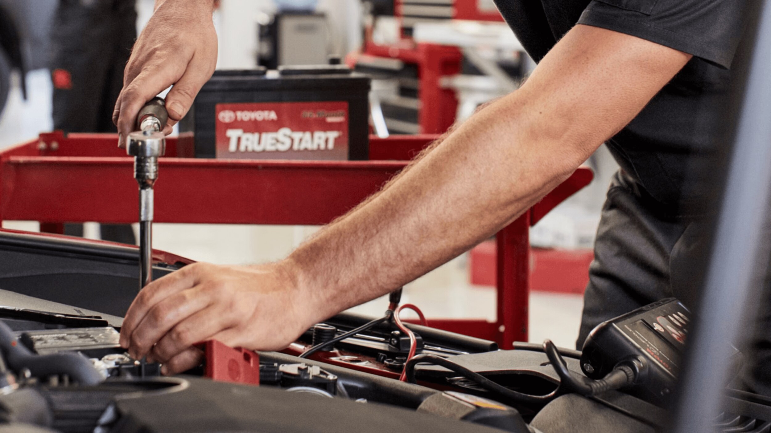 A pair of hands working on the engine of a vehicle in a garage