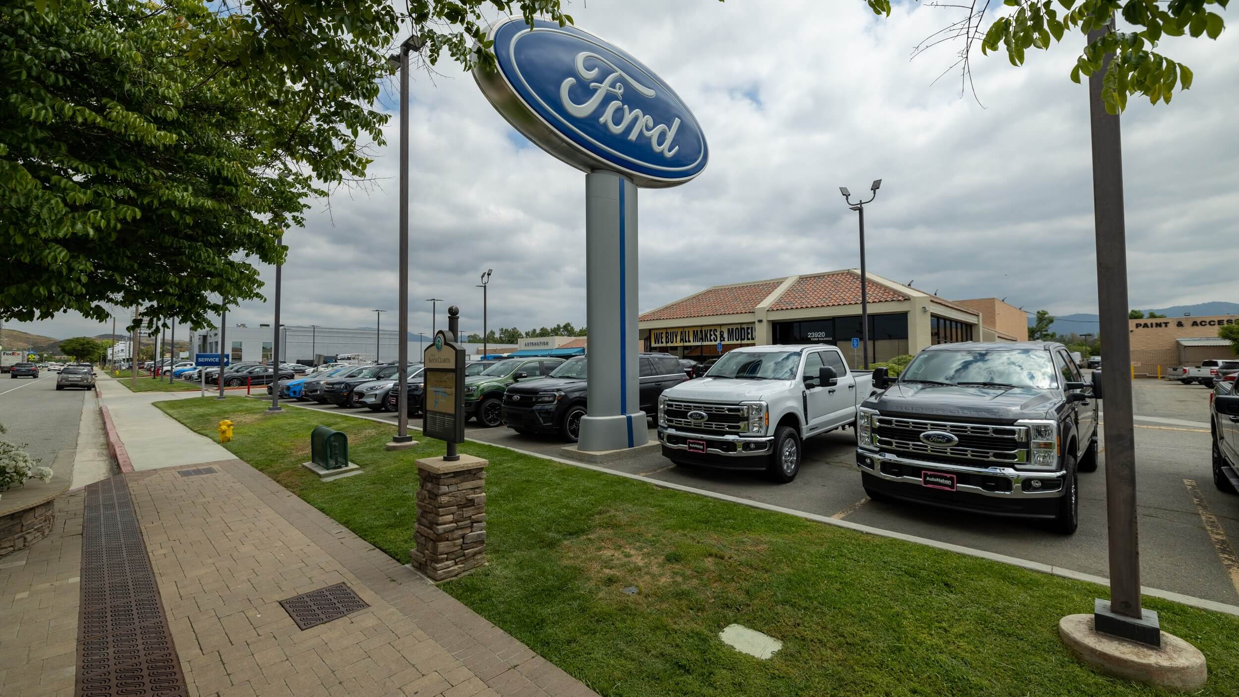 Exterior view of the AutoNation Ford dealership in Valencia, CA, trucks are parked under a Ford sign, shot from the sidewalk
