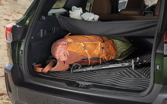 A dog resting on a bed in the open cargo area of the Outback