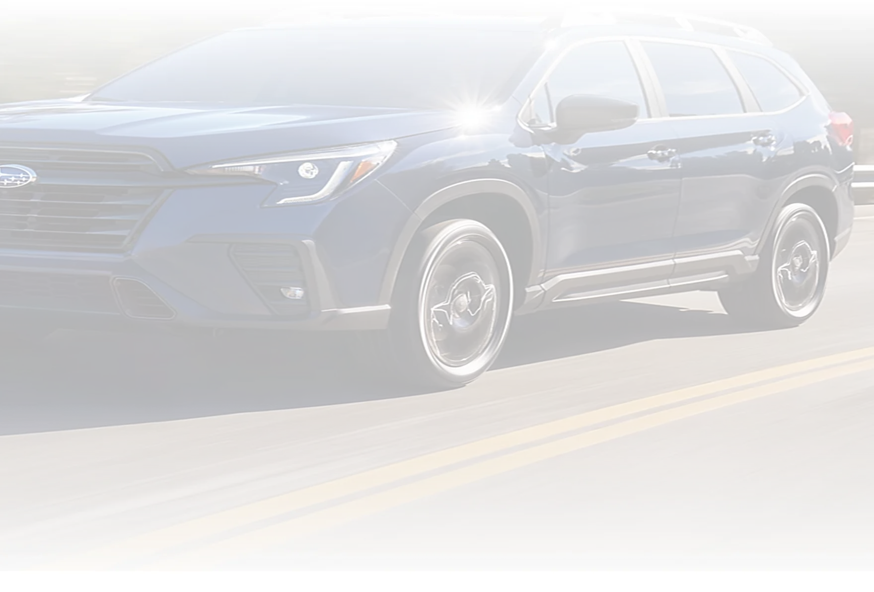 A dark Subaru Outback travelling a tree-lined highway