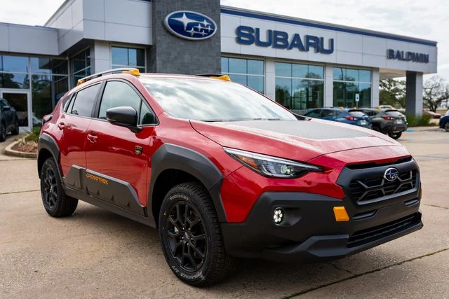 A red Subaru Crosstrek Wilderness parked in front of the Baldwin Subaru showroom