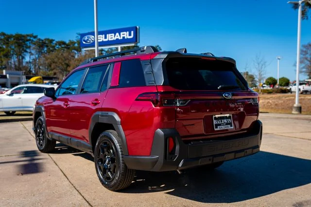 A red Subaru Outback backed into a parking space beneath the Baldwin Subaru sign on a clear day