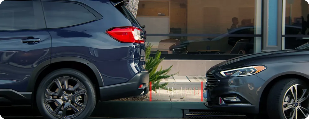 A Subaru Outback reversing toward a parked car with a red proximity warning