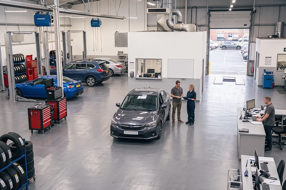 The Baldwin Subaru service floor with a gray Subaru in the centre bay while an advisor and technician review a checklist together