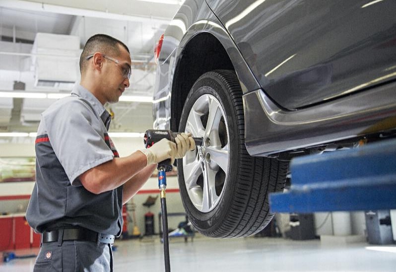 Toyota service technician putting tires on Toyota service tech changing tires