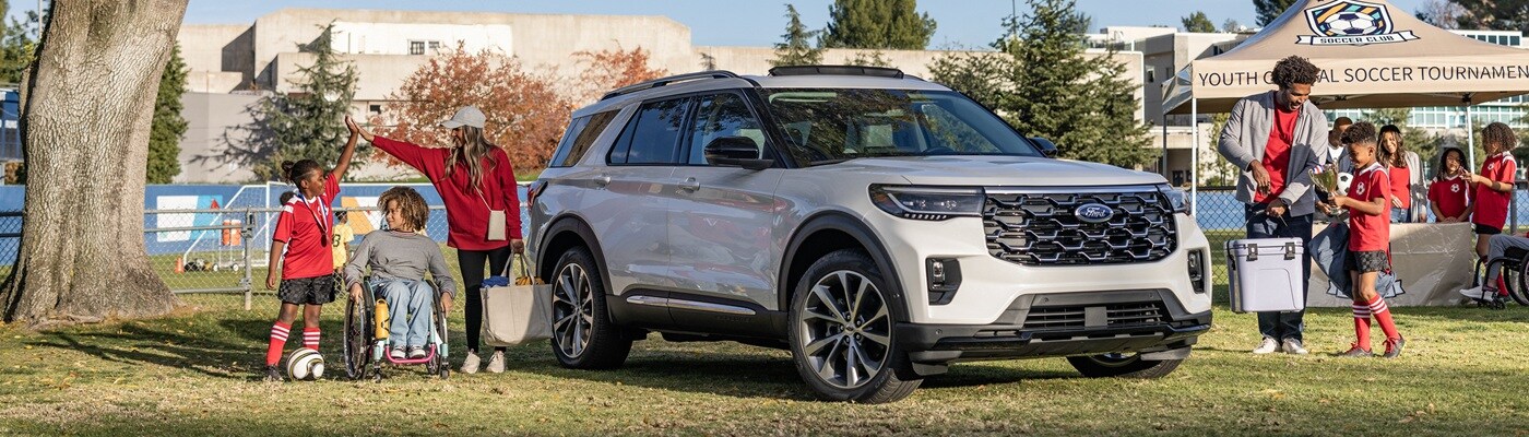 Ford Explorer White Ford Explorer parked on a rec field and surrounded by people