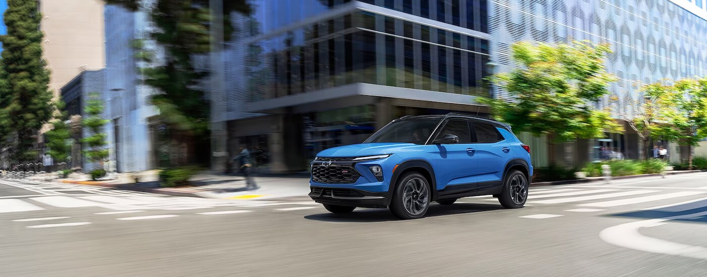 A blue 2024 Chevy Trailblazer for sale driving through a city.