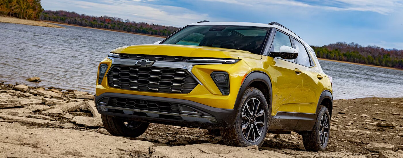 A yellow 2025 Chevy Trailblazer ACTIV parked on a rocky beach.