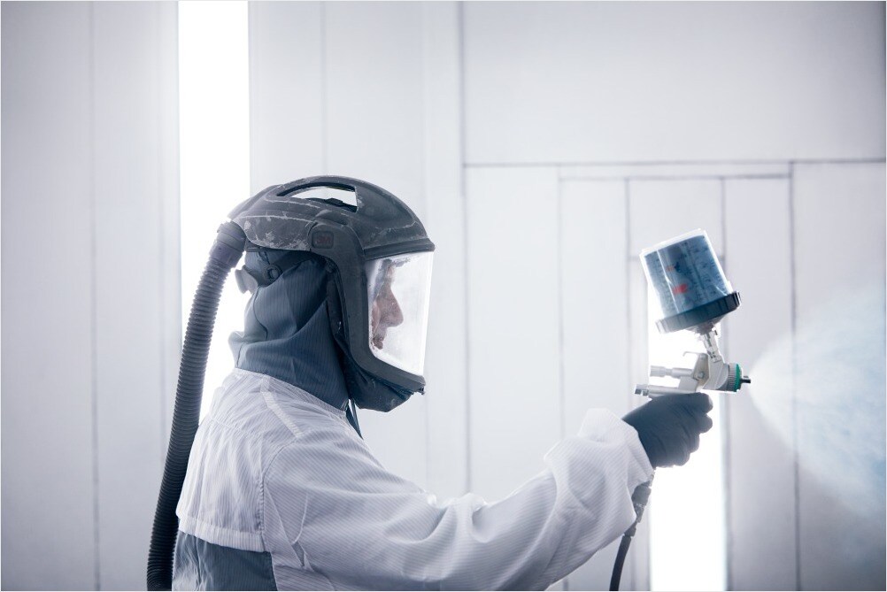 Volvo auto body repair with paint spray and technician in protective suit.jpg