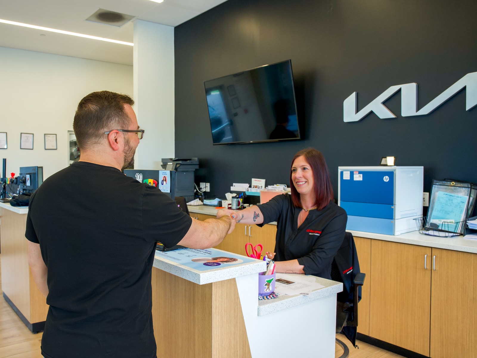 A customer shaking hands with a Bergey's Kia service advisor at the service desk in Colmar, Pennsylvania.