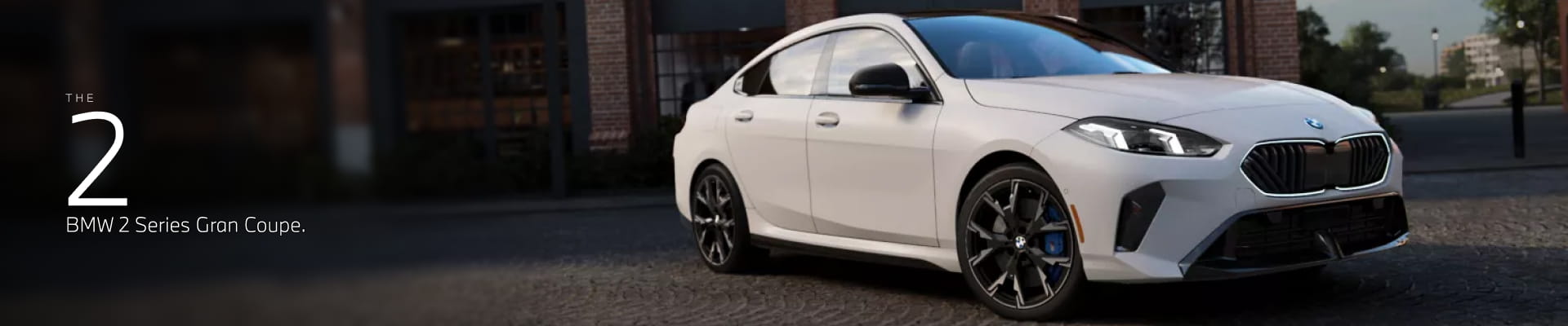 2026 BMW 2 Series Gran Coupe in white parked in front of an industrial brick building