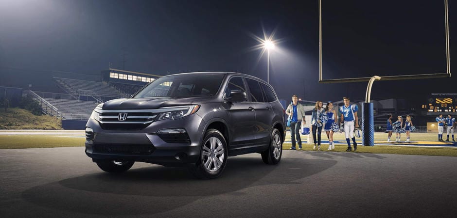 Best Honda SUV for Families A dark grey Honda Pilot parked near a football field