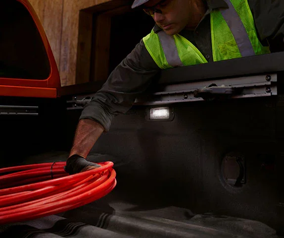Nissan Frontier bed with bed lighting on, the load area to inspect for wear on a used truck