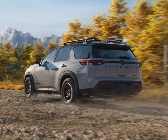 Nissan Pathfinder in red on mountain terrain, a three-row SUV for Tacoma families heading to Rainier