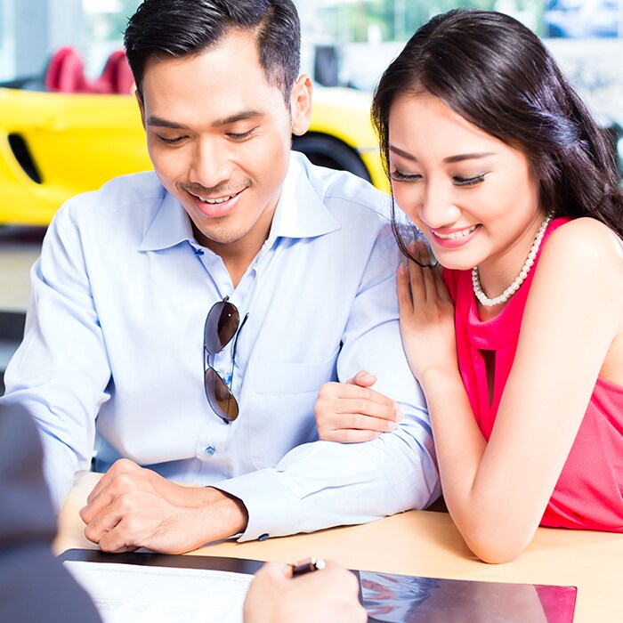 couple looking at paperwork in car dealership for loan or lease.jpg