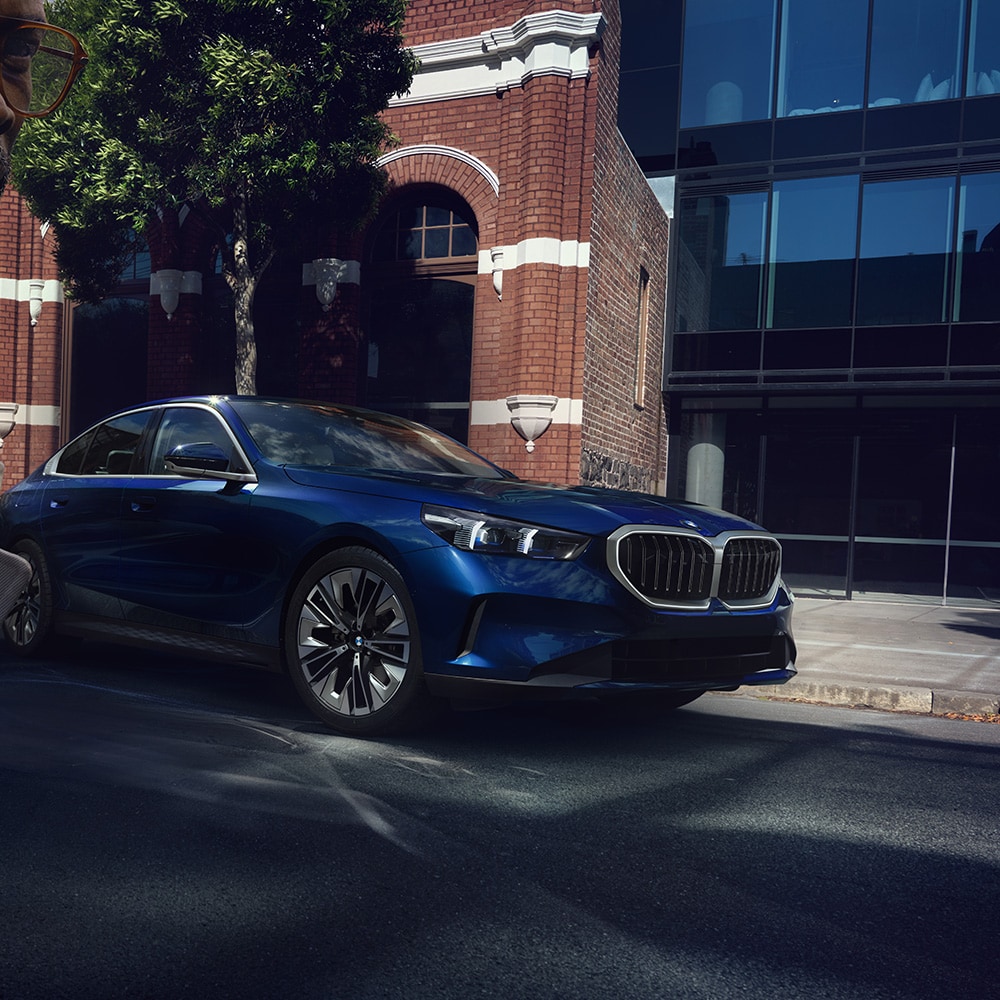 blue BMW 5 series parked on city street.