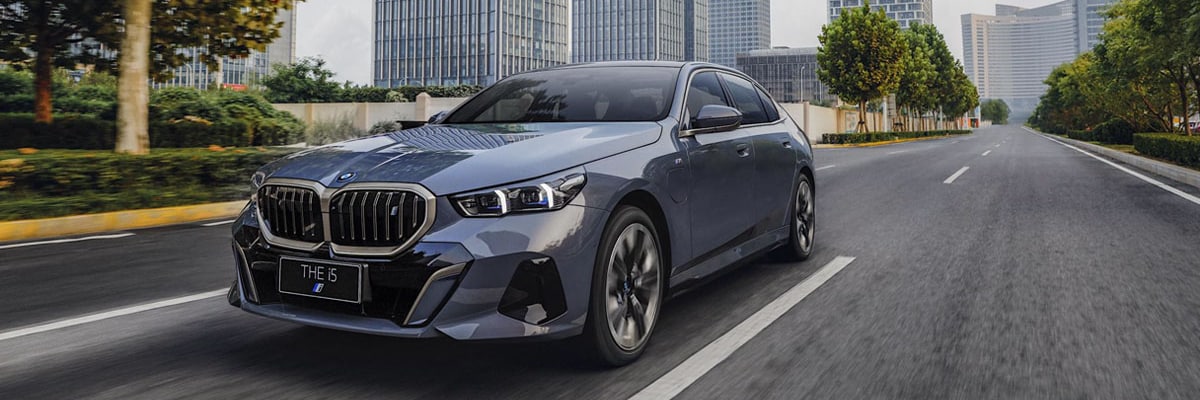 A 2024 BMW i5 driving down a city street.