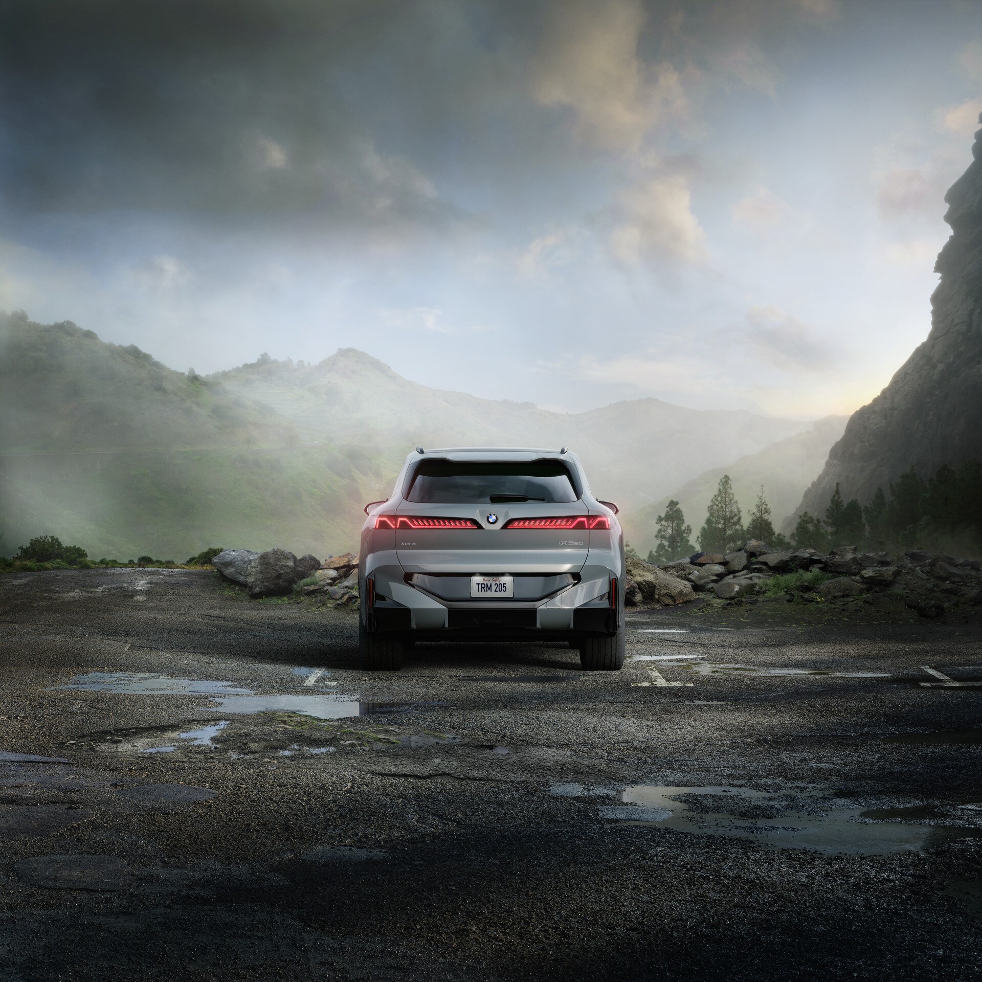Rear exterior of the new BMW X5 with illuminated taillights against a mountain landscape