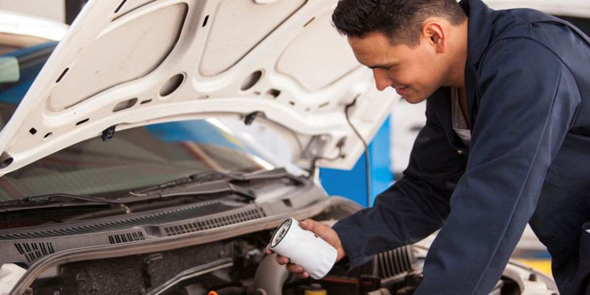Car service technician performing oil change leaning over engine_2.jpeg