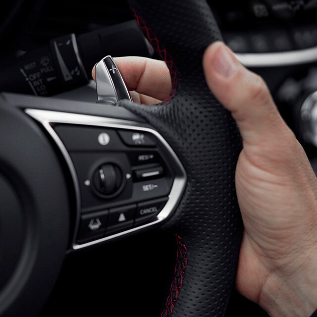 All-New 2022 Acura TLX at Bobby Rahal Acura | Hand Gripping Steering Wheel with Red Accents of 2022 Acura TLX with Index Finger on Paddle Shifter