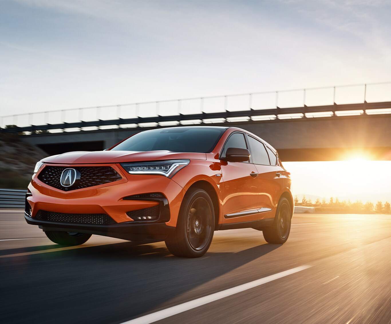What is Tire and Rim Protection? | Bobby Rahal Acura | Orange Acura RDX driving down the highway with the sunset coming down behind it