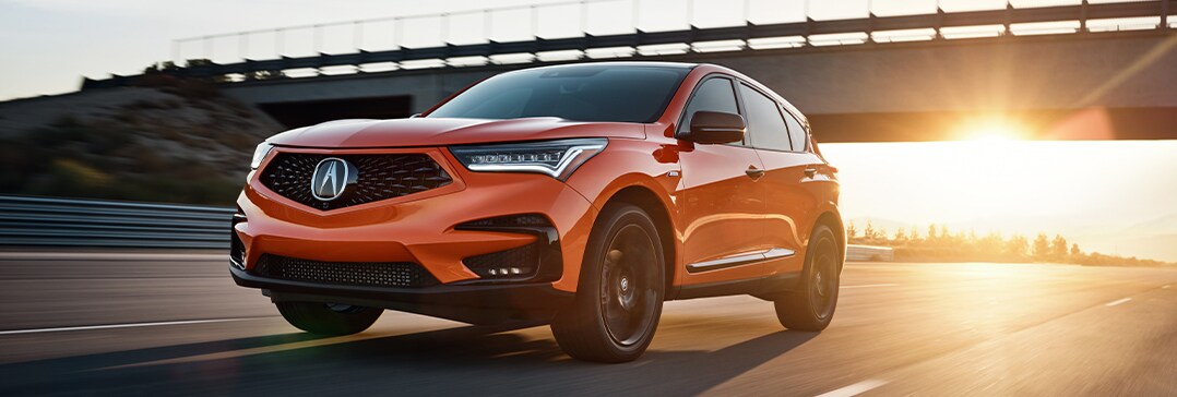 Compare the 2021 Acura RDX vs. the 2021 BMW X3 at Bobby Rahal Acura | RDX driving on highway with sun glaring behind